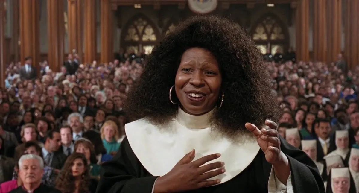 Whoopi Goldberg conducts a choir wearing a nun's habit but no wimple.
