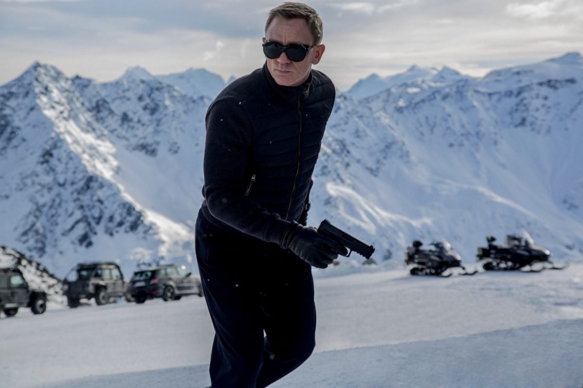 James Bond standing in the mountains with sunglasses on in Spectre