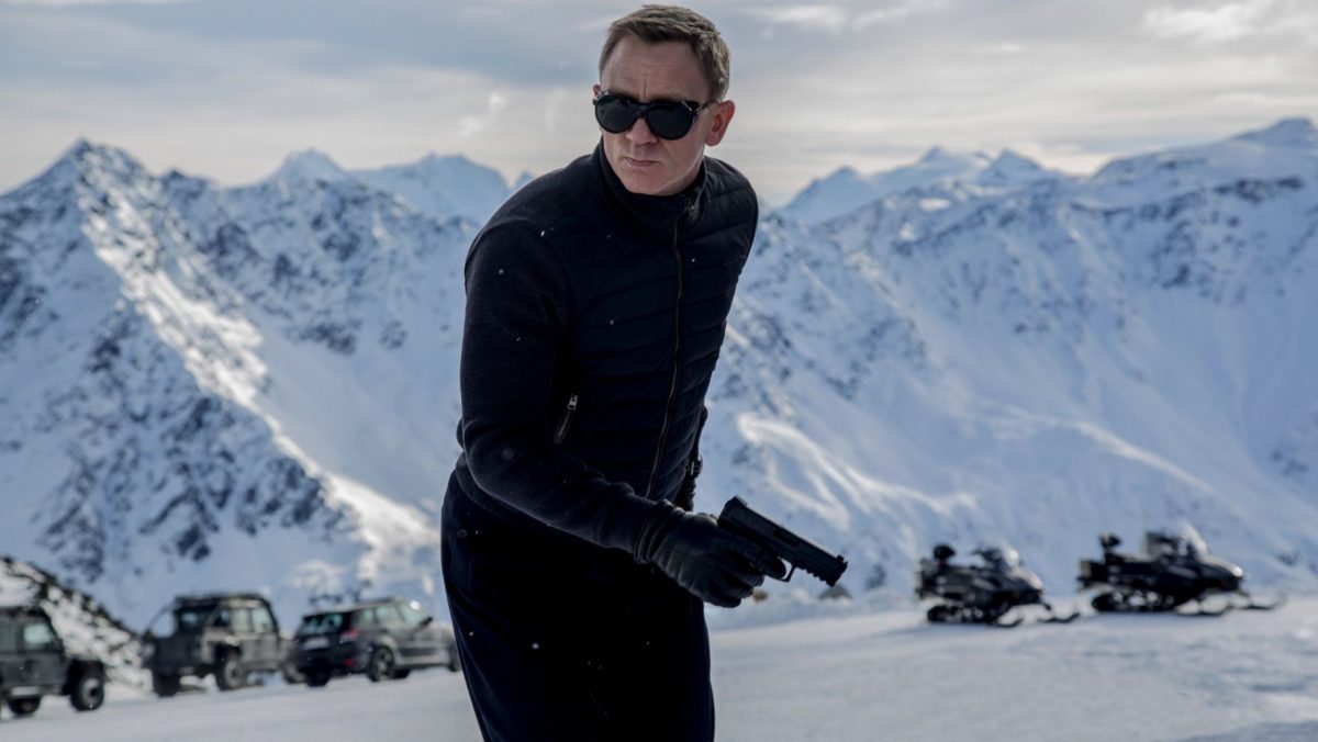 James Bond standing in the mountains with sunglasses on in Spectre