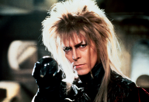 David Bowie as Jareth, looking at the camera and holding a crystal orb in a black-gloved hand.