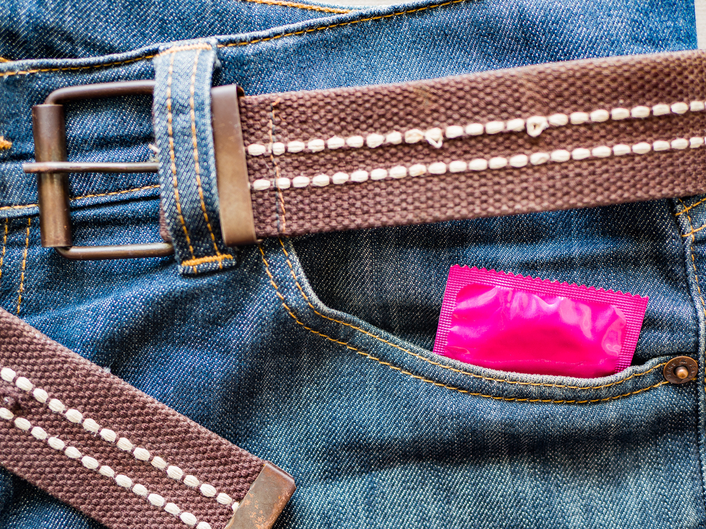 A pink condom wrapper peek out of a jeans pocket
