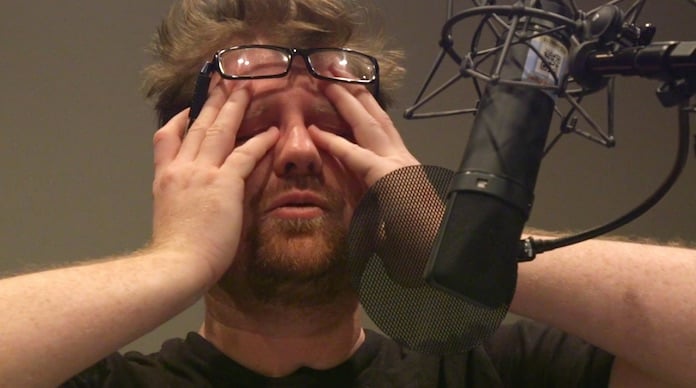 justin roiland, voice of rick sanchez and morty smith, rubs his eyes in front of a microphone