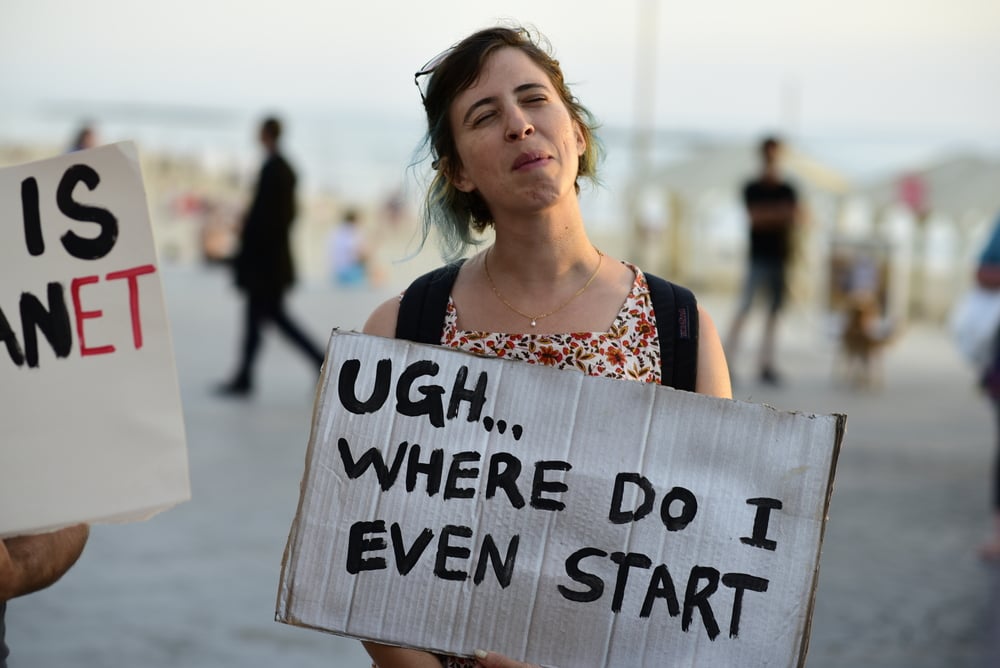 Woman holding sign that says, "Ugh, where do I even start?"