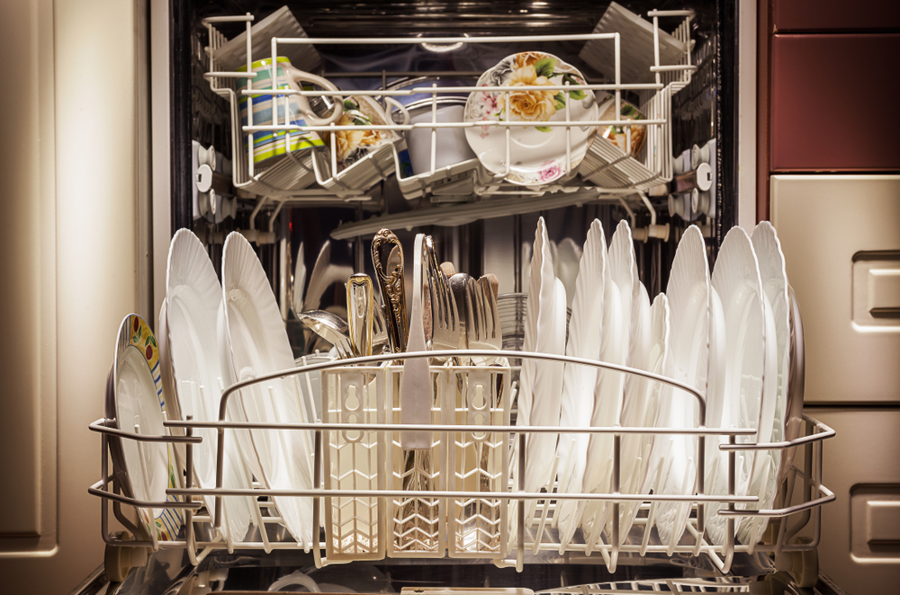 Shutterstock image of dirty dishes in a dishwasher, representing domestic labor