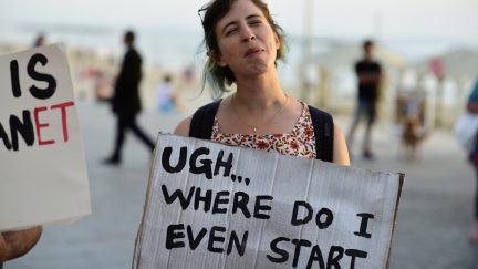 Woman holding sign that says, 