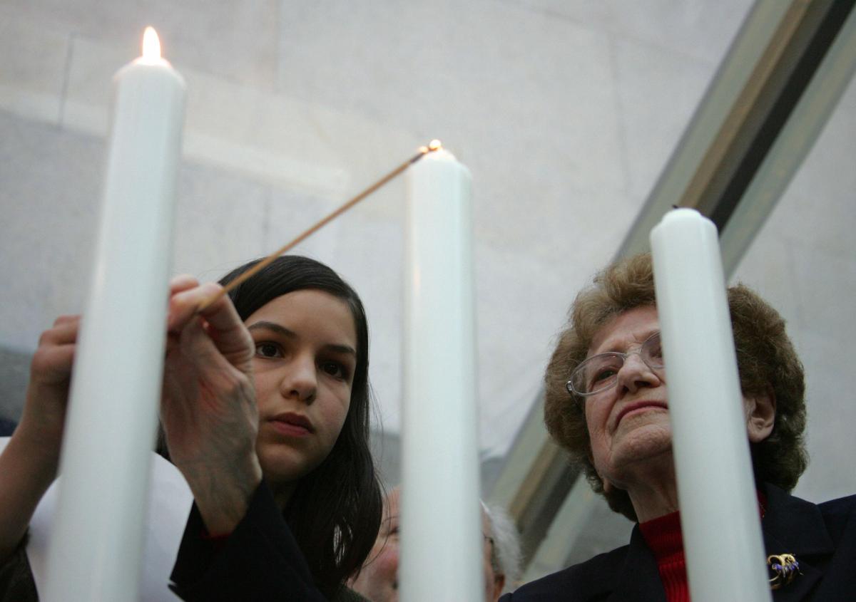 Paris, FRANCE: A woman lights a candle, 24 April 2006, at the holocaust memorial in Paris, as they attend a ceremony to commemorate the 76.000 Jewish victims sent from France to concentrations camp between 1942 and 1944, as part of the "Yom HaShoah", a day marking the annual Holocaust remembrance.