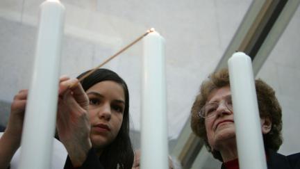 Paris, FRANCE: A woman lights a candle, 24 April 2006, at the holocaust memorial in Paris, as they attend a ceremony to commemorate the 76.000 Jewish victims sent from France to concentrations camp between 1942 and 1944, as part of the 