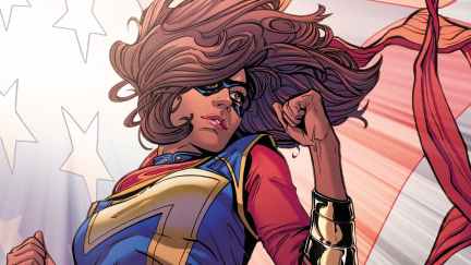 Kamala Khan poses with an upraised fist in front of an American flag.