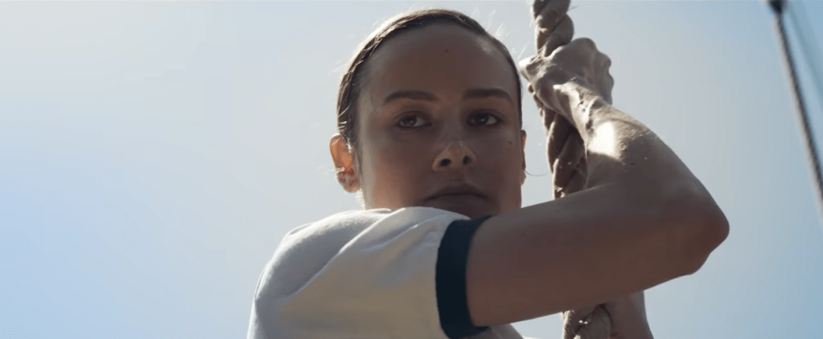 Brie Larson climbs a rope as Carol Danvers in Captain Marvel.