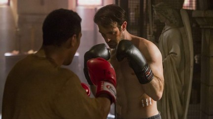 Matt Murdock (Charlie Cox) is shirtless and wearing boxing gloves as he trains with another person wearing boxing gloves in a scene from 'Daredevil'