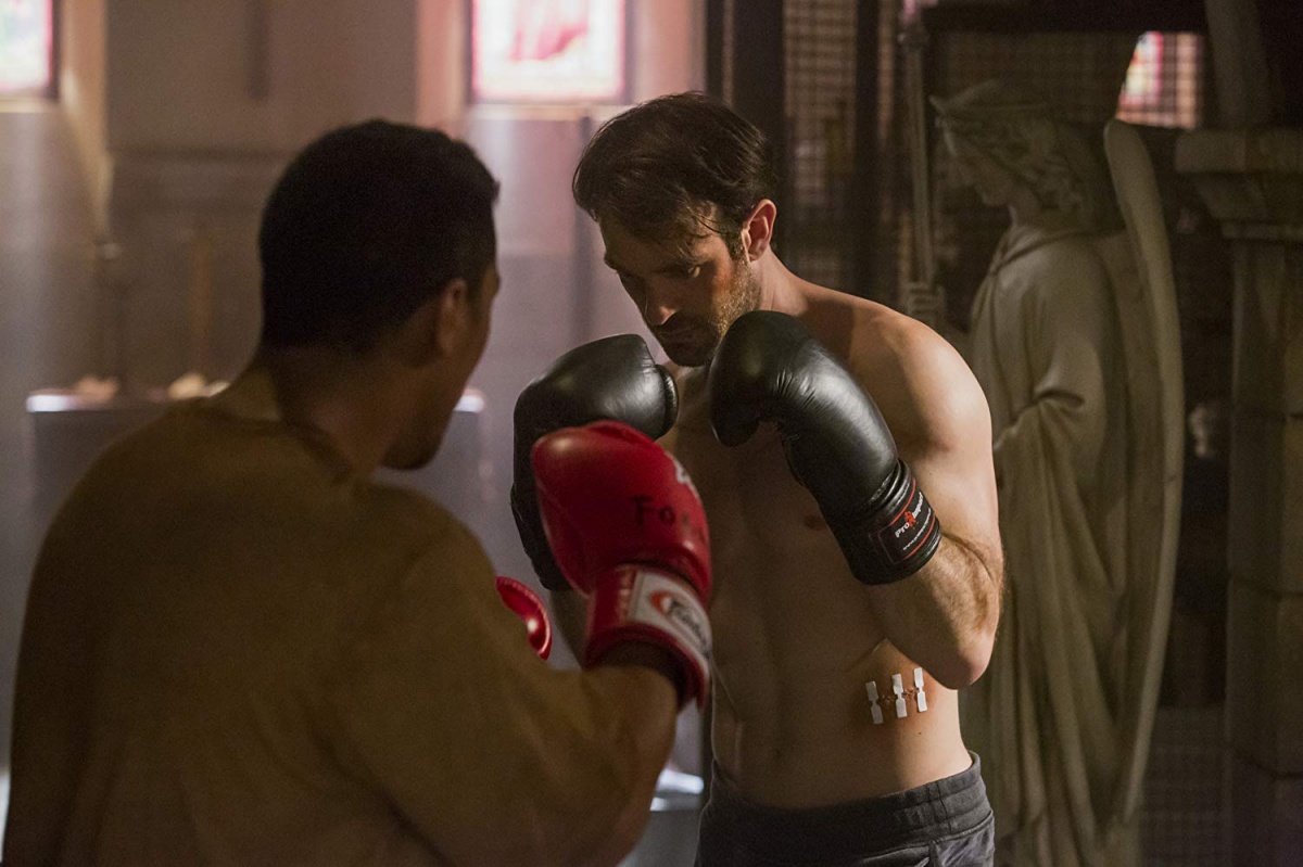 Matt Murdock (Charlie Cox) is shirtless and wearing boxing gloves as he trains with another person wearing boxing gloves in a scene from 'Daredevil'