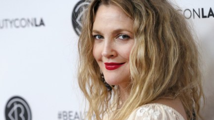Drew Barrymore poses and smiles on a red carpet.