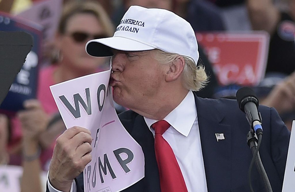 Trump kisses a sign reading Women for Trump