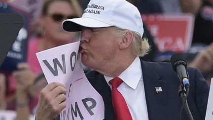 Trump kisses a sign reading Women for Trump