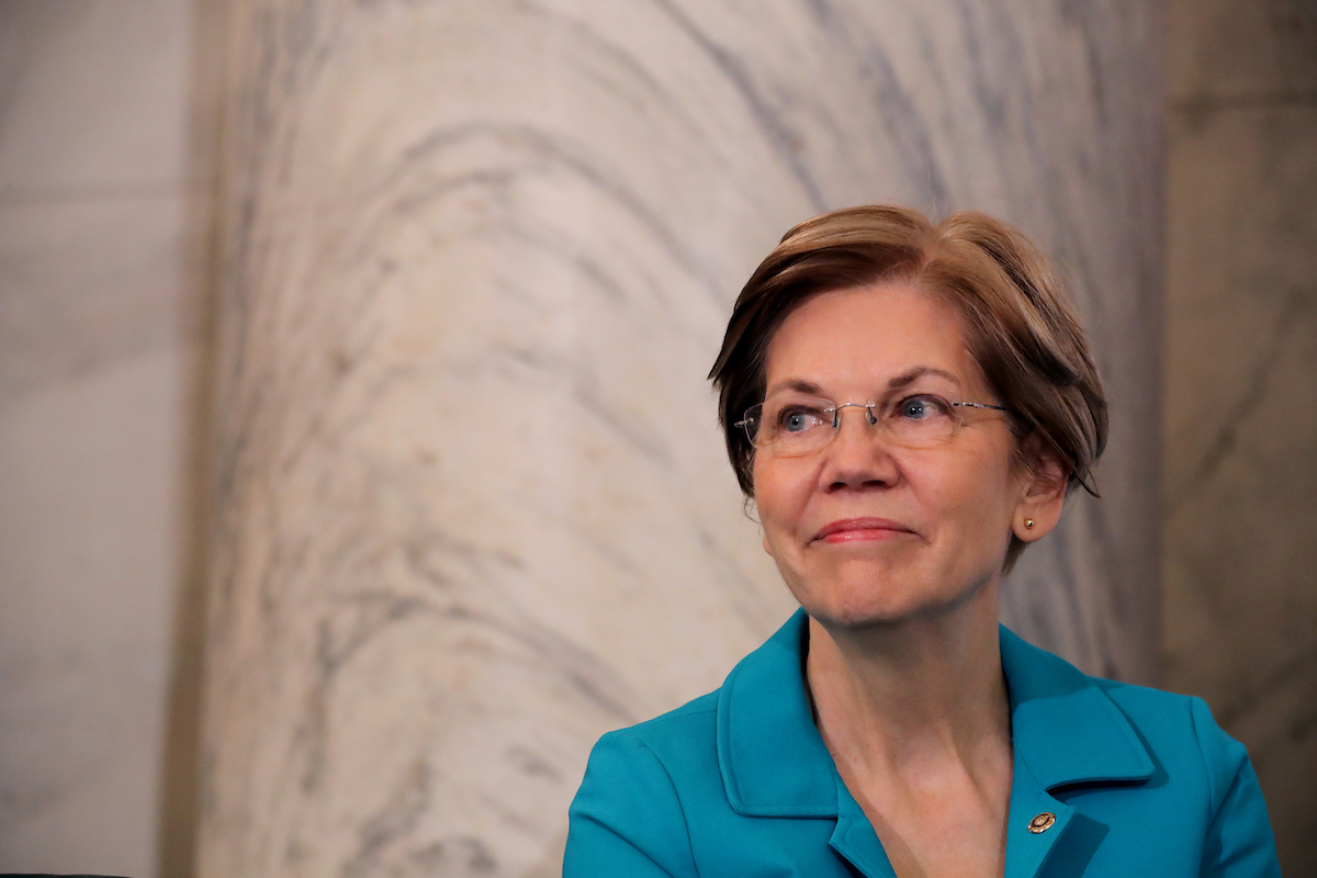 Elizabeth Warren stands against a marble wall looking charming and presidential.