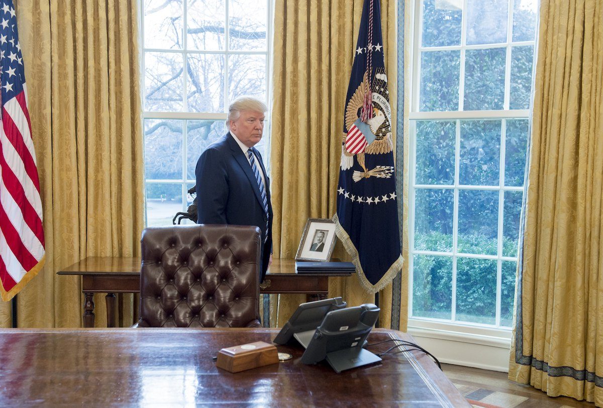 Donald Trump looks very small standing behind his desk in the Oval Office.