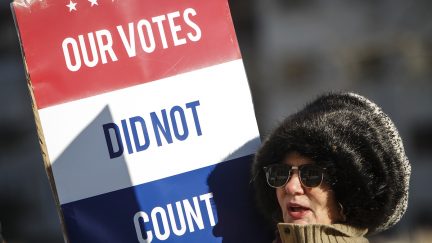 Protestor holds a sign reading 