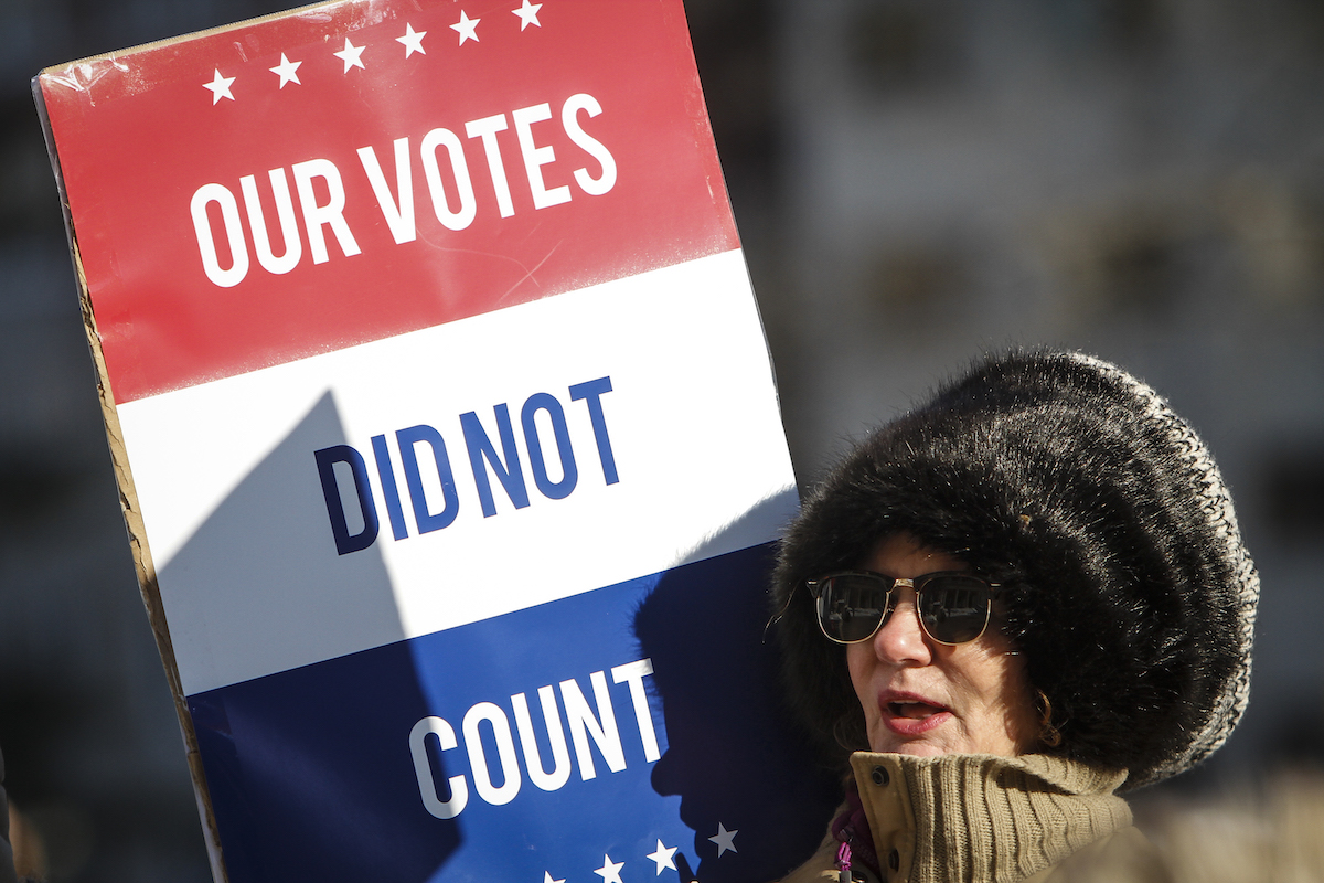 Protestor holds a sign reading "Our votes did not count."