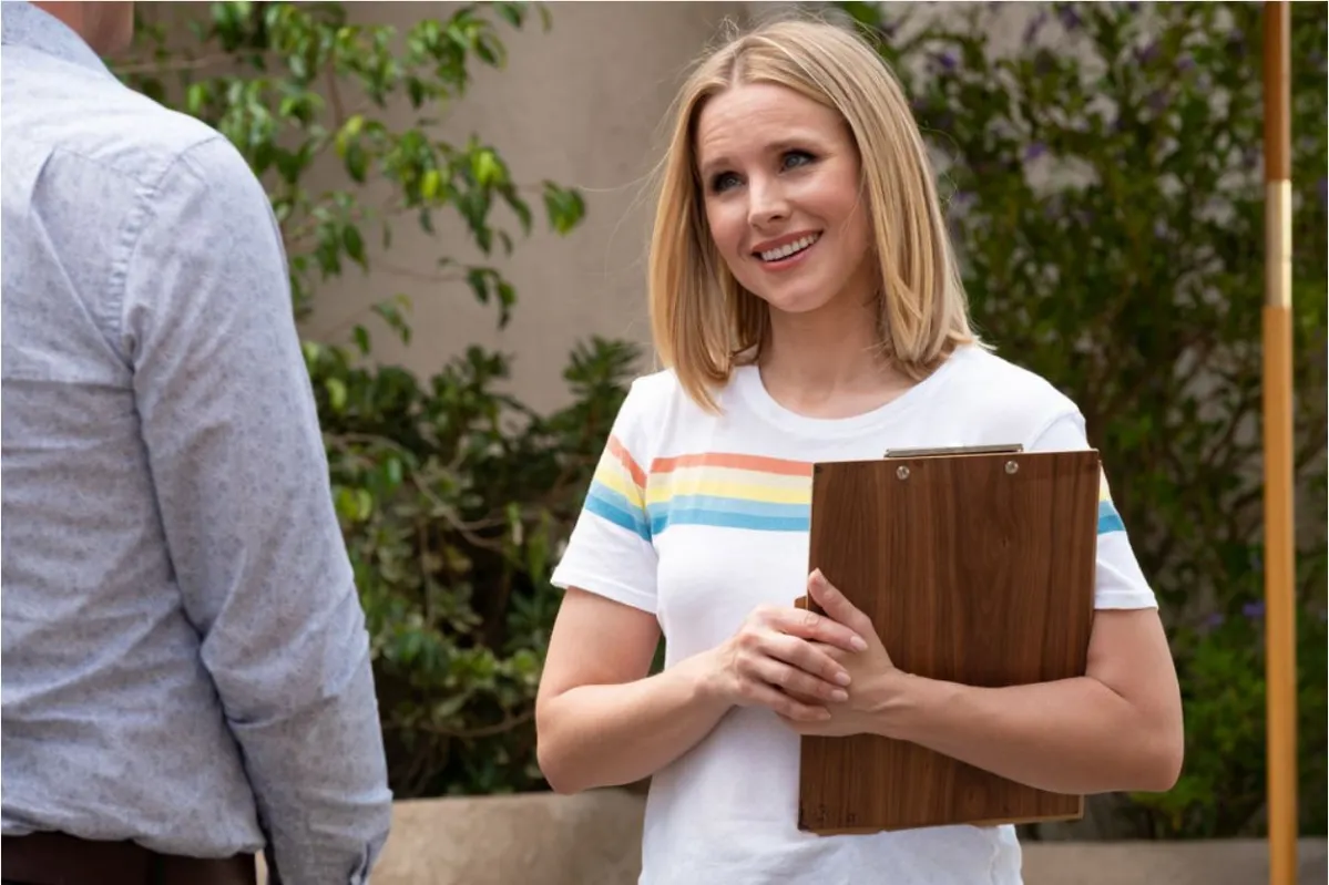 A white woman stands smiling with a clipboard