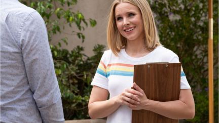 A white woman stands smiling with a clipboard