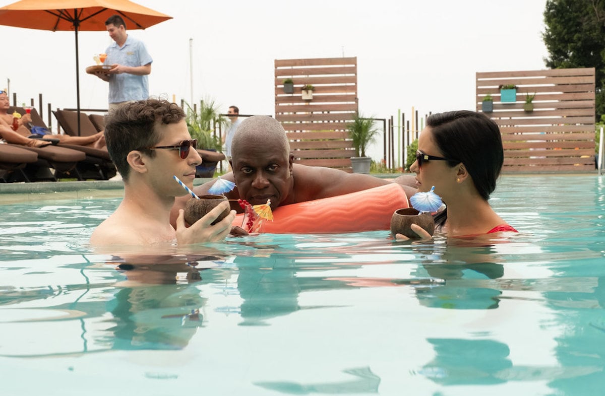 BROOKLYN NINE-NINE -- "Honeymoon" Episode 601 -- Pictured: (l-r) Andy Samberg as Jake Peralta, Andre Braugher as Ray Holt, Melissa Fumero as Amy Santiago, drinking tropical cocktails from coconuts in a swimming pool