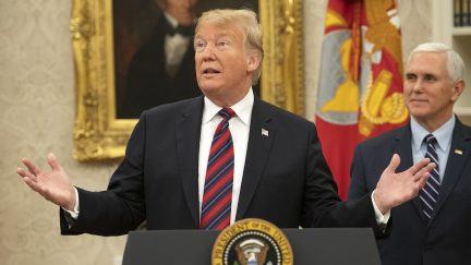 Donald Trump stands at a podium in the Oval Office with Mike Pence behind him.