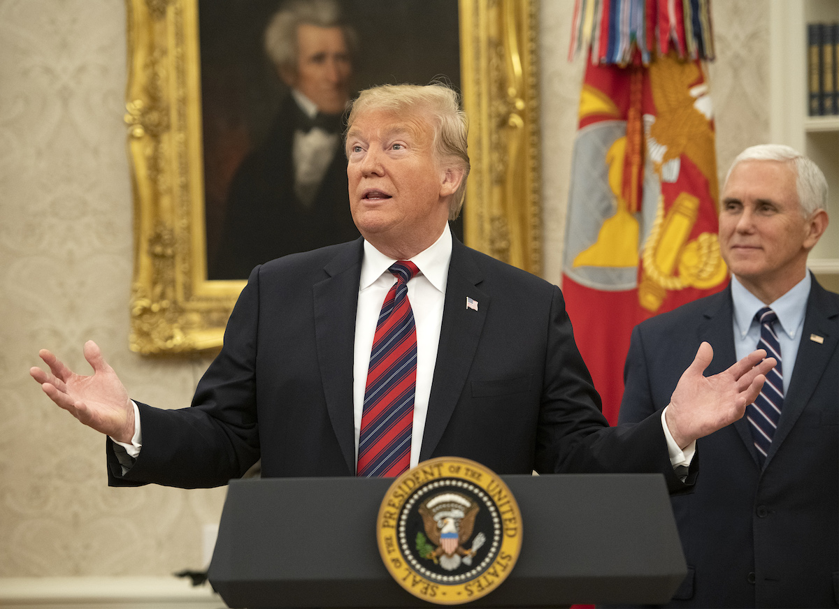 Donald Trump stands at a podium in the Oval Office with Mike Pence behind him.