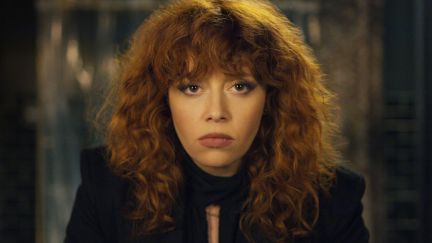 A red haired white woman stares intensely into the camera.