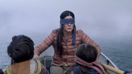 Sandra Bullock as Malorie, paddling a boat with her children in Bird Box.