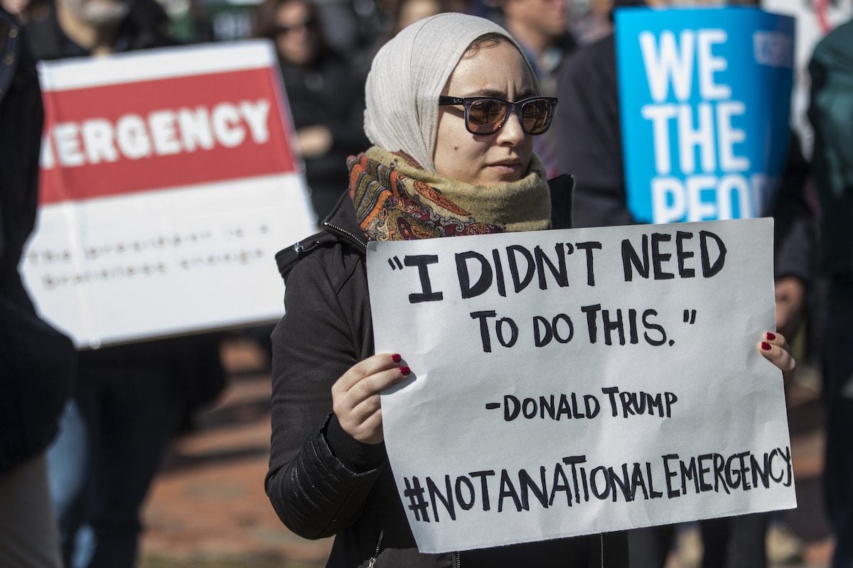 Protestor holds a sign reading "'I didn't need to do this.' -Donald Trump #NotaNationalEmergency" during an ACLU demonstration