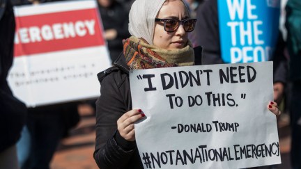 Protestor holds a sign reading 