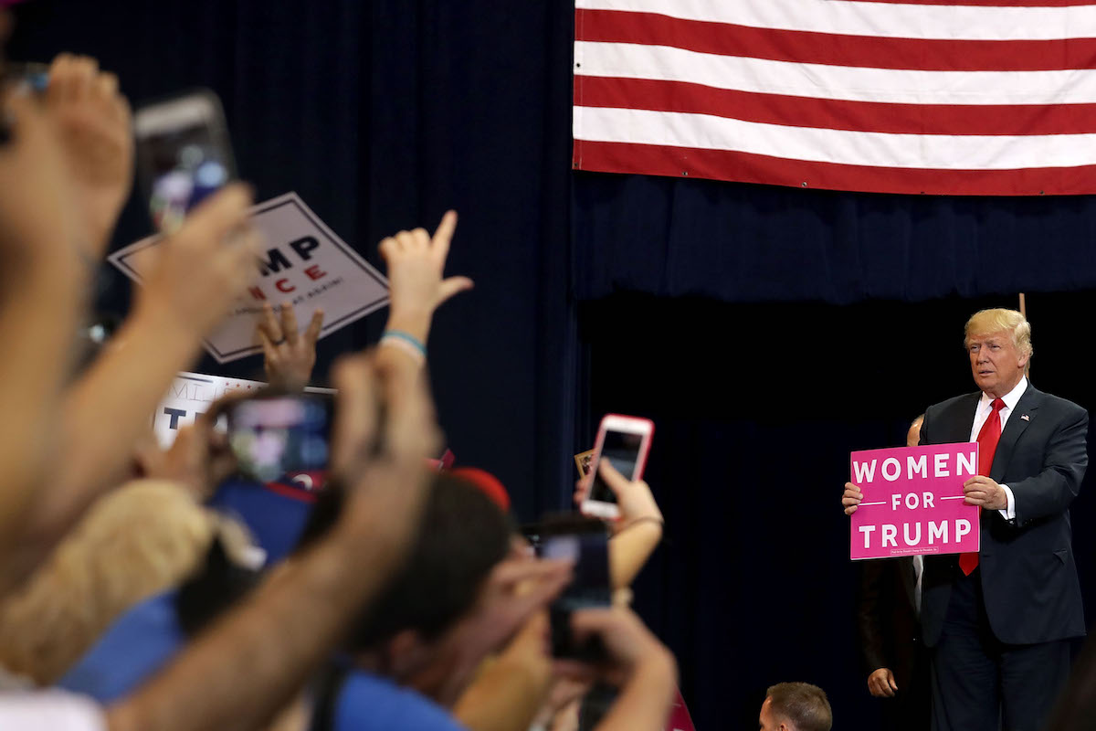 Donald Trump holds a Women for Trump sign at a campaign rally