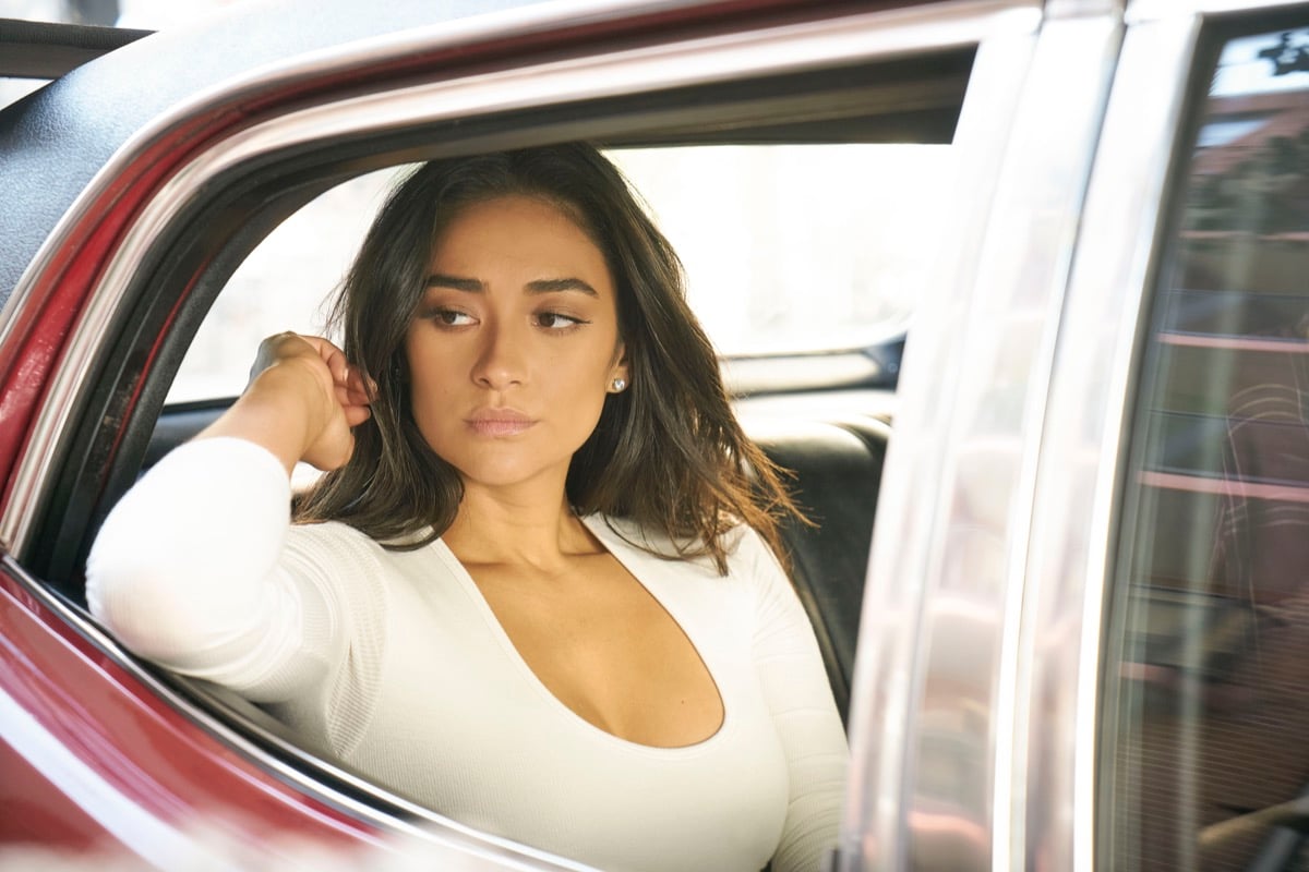 Shay Mitchell as Peach Salinger sitting in a car in Netflix's You.