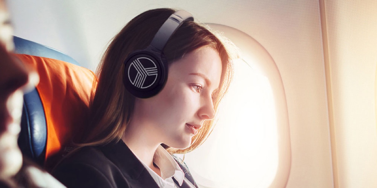 A woman listening to headphones on an airplane.