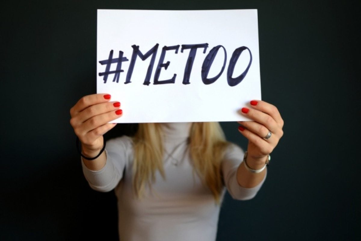 A woman holds a sign that reads "#MeToo."