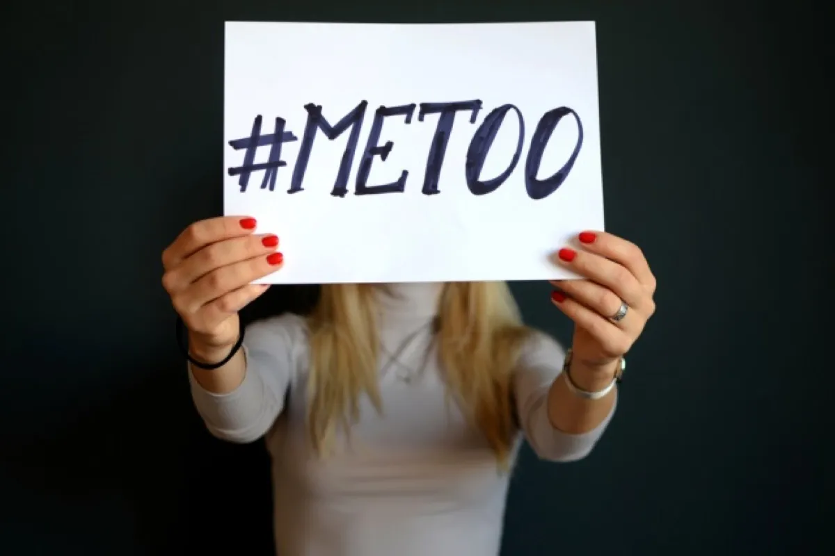 A woman holds a sign that reads "#MeToo."