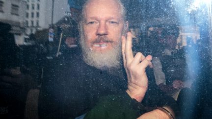 Julian Assange throwing up a peace sign after he was arrested