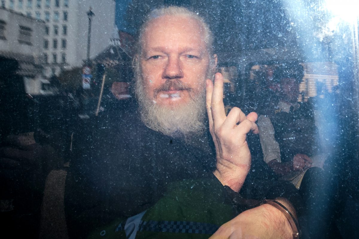 Julian Assange throwing up a peace sign after he was arrested