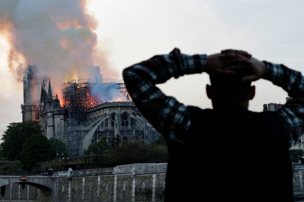 A man watches the landmark Notre-Dame Cathedral burn, engulfed in flames, in central Paris on April 15, 2019. - A huge fire swept through the roof of the famed Notre-Dame Cathedral in central Paris on April 15, 2019, sending flames and huge clouds of grey smoke billowing into the sky. The flames and smoke plumed from the spire and roof of the gothic cathedral, visited by millions of people a year. A spokesman for the cathedral told AFP that the wooden structure supporting the roof was being gutted by the blaze. (Photo by Geoffroy VAN DER HASSELT / AFP) (Photo credit should read GEOFFROY VAN DER HASSELT/AFP/Getty Images)