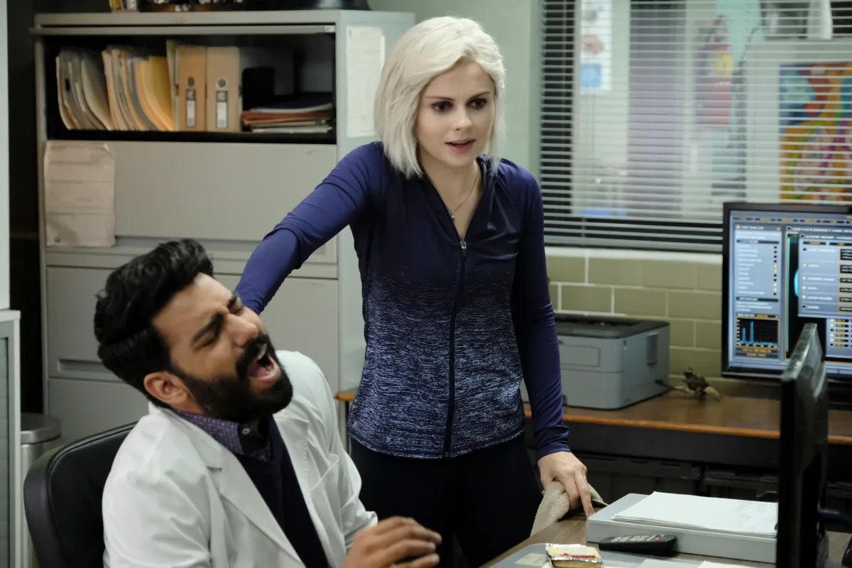 Rahul Kohli as Ravi and Rose McIver as Liv, standing in an office.