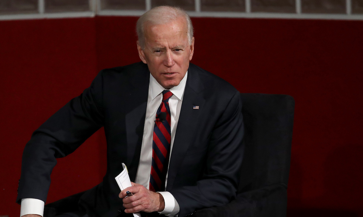 Joe Biden seated, leaning forward and speaking.