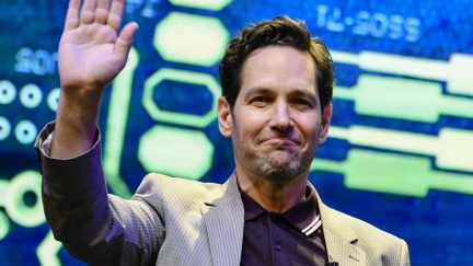 Paul Rudd waves in front of a colorful backdrop
