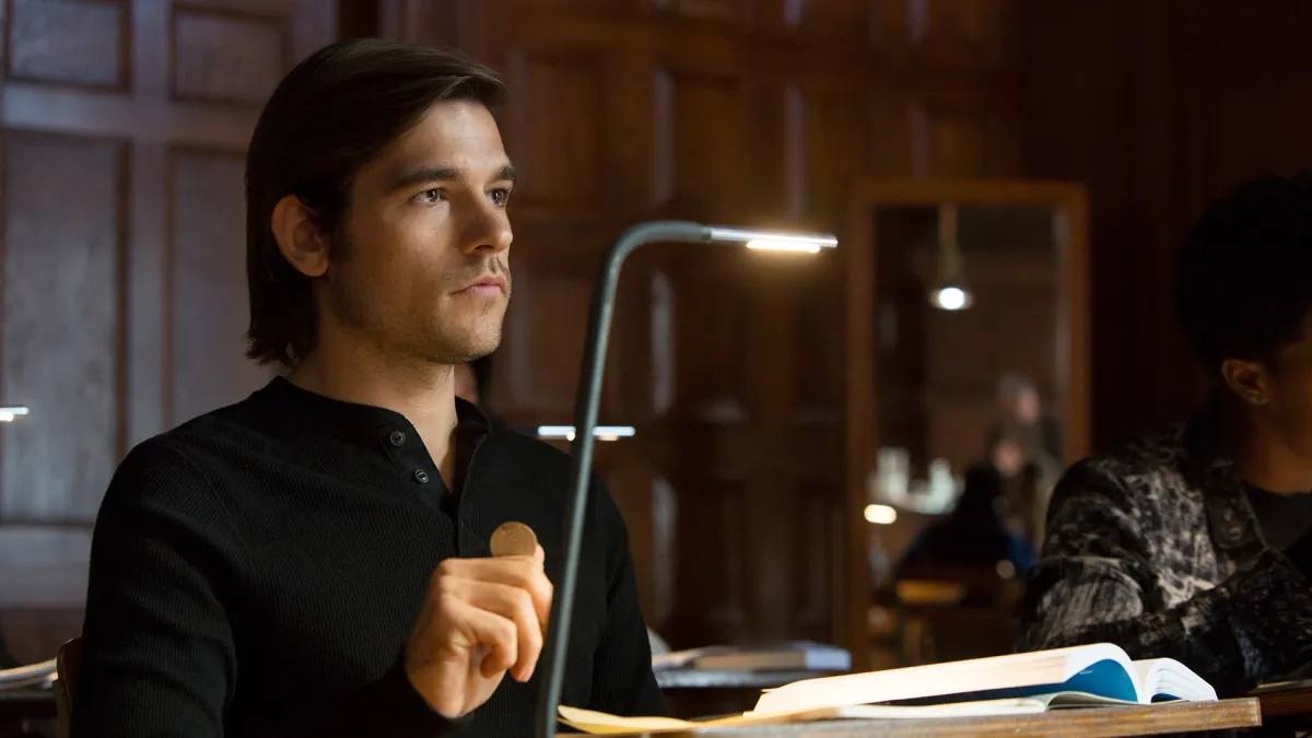 Quentin sits at a desk in Syfy's The Magicians.