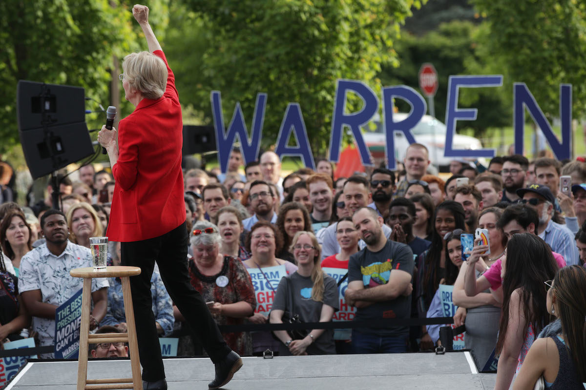Elizabeth Warren onstage at a rally with supporters in front of her.