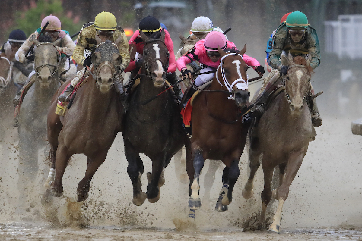 Horses race in the Kentucky Derby on a muddy track.