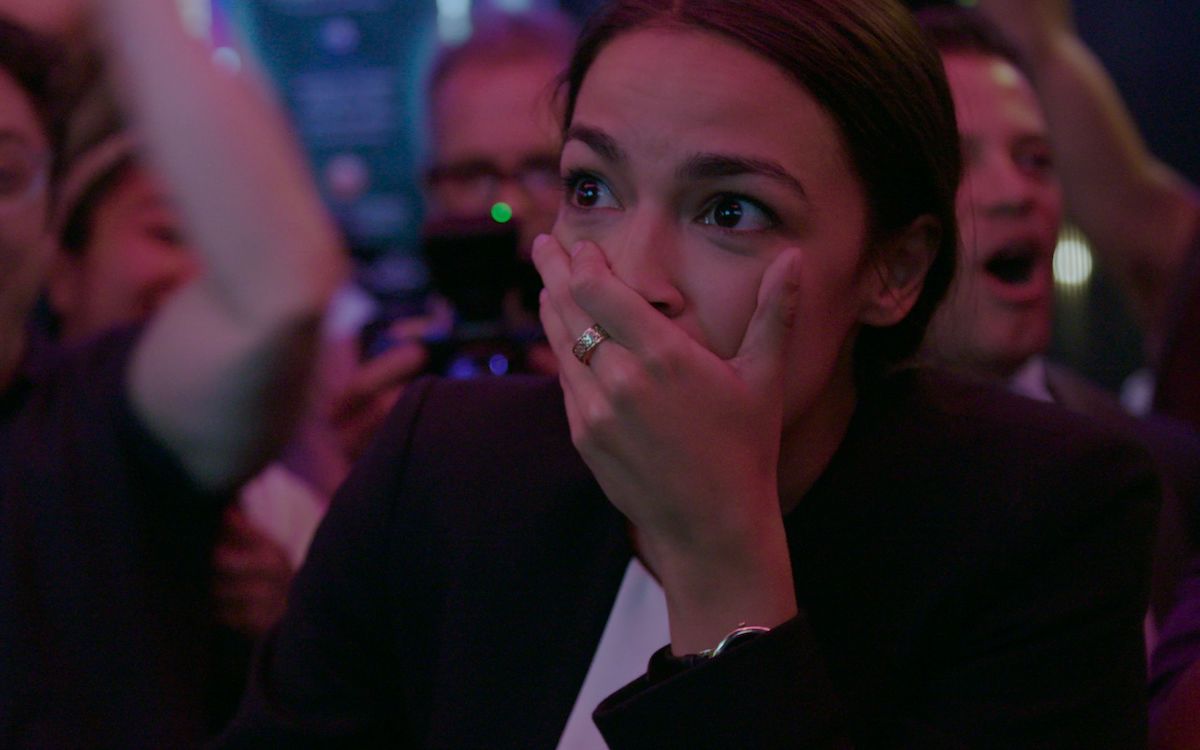 AOC covers her mouth, reacting to the news that she'd won her primary election.