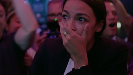 AOC covers her mouth, reacting to the news that she'd won her primary election.