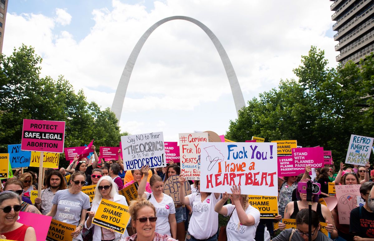 Protesters hold signs as they rally in support of Planned Parenthood in front of the St Louis arch.