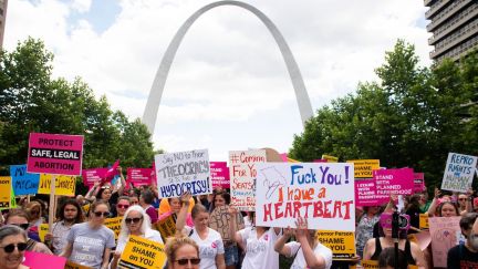 Protesters hold signs as they rally in support of Planned Parenthood in front of the St Louis arch.
