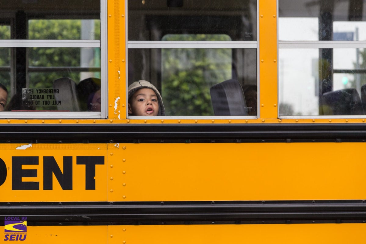 A small child looks out of a school bus window.